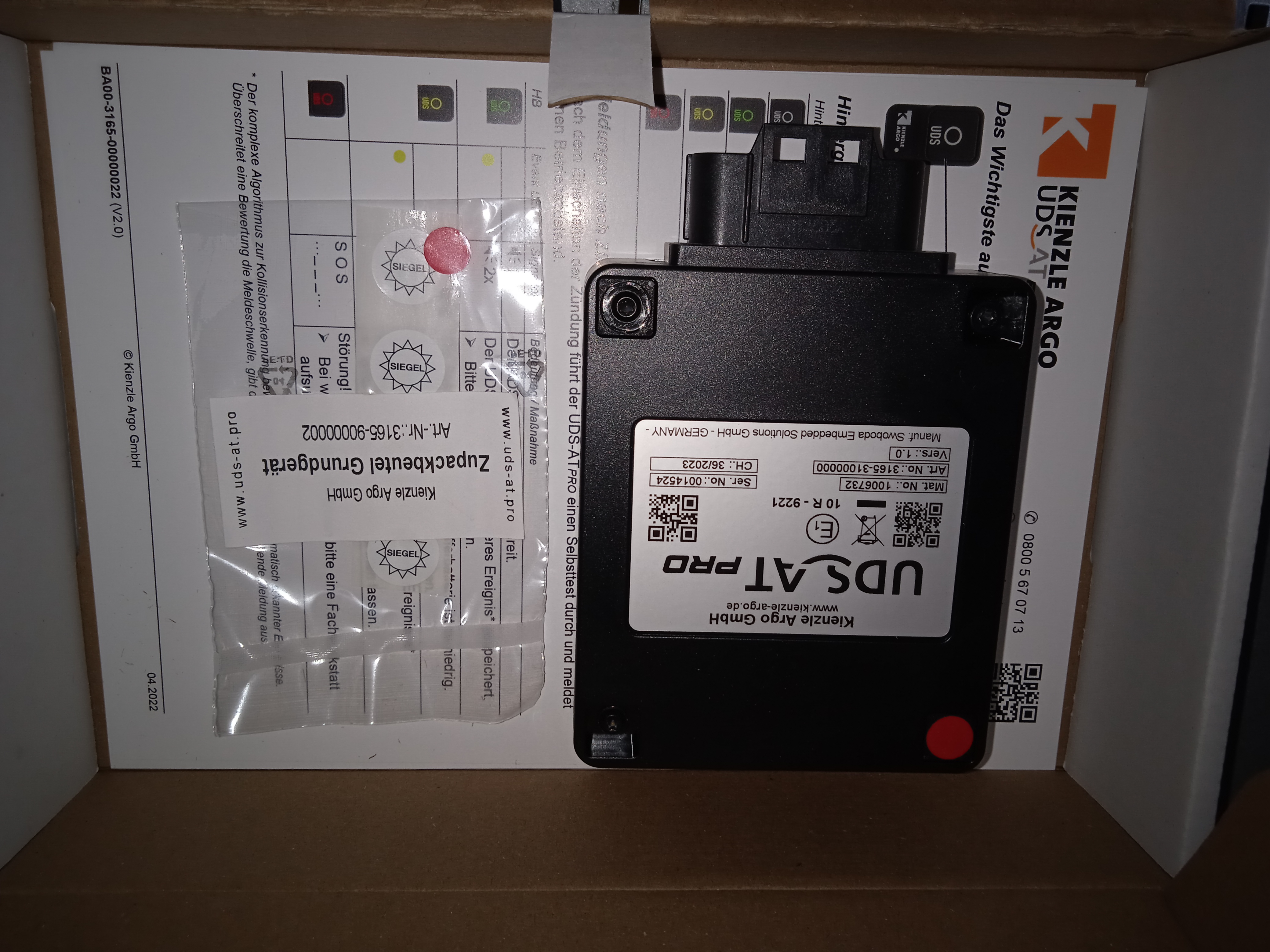 Lieferumfang des UDS-AT Pro mit GNSS-Modul und CIA 447 Freischaltung mit Plombenkappe und Klebesiegel und Bedienungsanleitung 